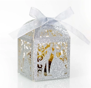 Detail of silver glitter wedding favor box with laser-cut silhouettes and silk ribbon