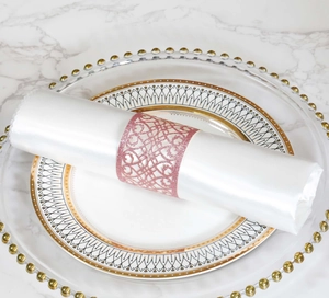 Macro view of pink glitter hollow-out napkin ring on white satin on marble table