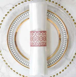 Detail of rose gold laser-cut napkin ring with heart pattern on white marble surface