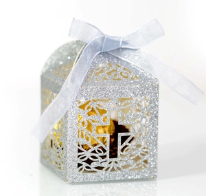 Detail of silver glitter laser-cut gift box with cross pattern and blue silk ribbon