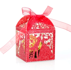 Macro shot of laser-cut wedding candy box with red glitter and groom-bride pattern