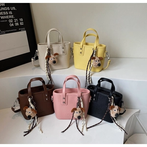 Group display of five colorful mini bucket bags with leather texture and plush dog charms