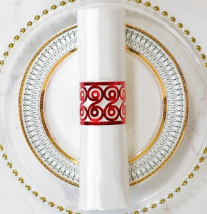 Detail of red laser-cut scroll napkin ring on white satin fabric over marble tabletop
