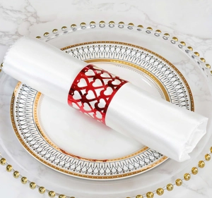Close-up of bright red napkin ring with laser-cut heart patterns on elegant tableware