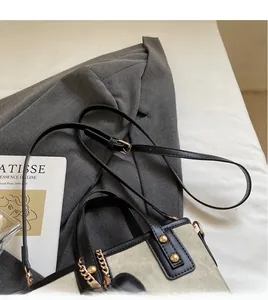 Détail d'un sac seau en toile avec clous dorés, chaîne et bandoulière réglable