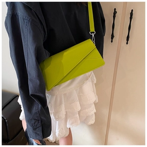 Close-up of bright green geometric crossbody bag worn by model over a blue outfit