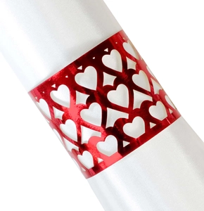 Detail of red hollow heart-shaped metal napkin ring on a white satin fabric napkin