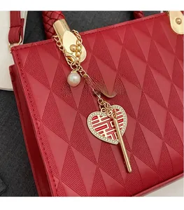 Detail of red wedding tote bag featuring quilted texture, gold hardware and pearl heart charm