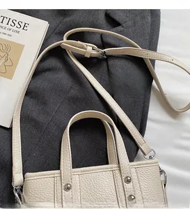 Detail view of cream bucket bag showing lychee grain texture and silver stud accents