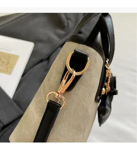 Détails de la boucle dorée et de la bordure en cuir noir sur un sac seau en toile beige