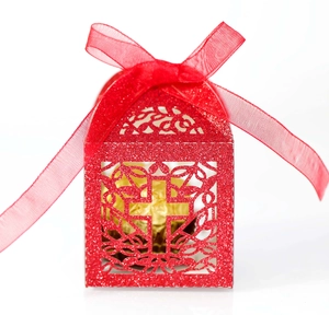 Detail of red glitter gift box with laser-cut cross design and festive silk ribbon