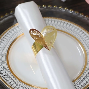 Détail du rond de serviette doré en forme de cœur évidé avec motifs floraux ciselés