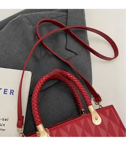 Detail of red quilted tote bag with woven handles and leather strap on a stylish background
