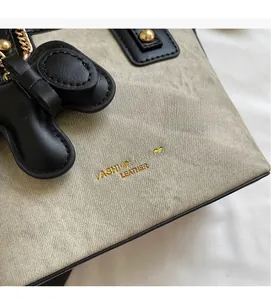 Gros plan détaillé sur la texture en toile beige avec finitions en cuir noir et logo doré