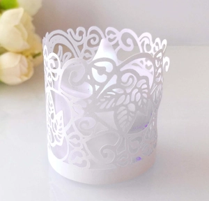 Macro detail of laser-cut paper candle shade with intricate heart and leaf patterns