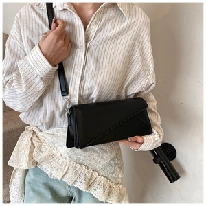 Detail shot of a black crossbody bag with a geometric folded design and silver hardware