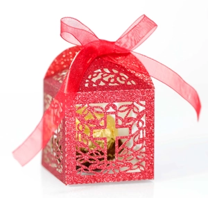 Detail of red glitter wedding favors box with laser-cut cross pattern and ribbon bow