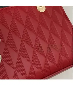 Detail of red leather tote featuring triangle embossed texture and gold metal hardware