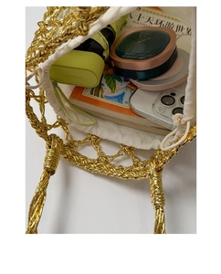 Close-up of golden hollow woven tote bag showing spacious interior with white drawstring liner