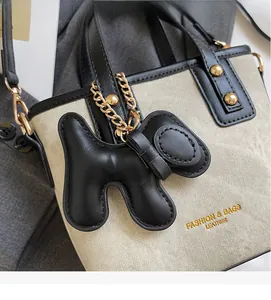 Détail du sac seau en toile avec bordure en cuir noir et breloque chien