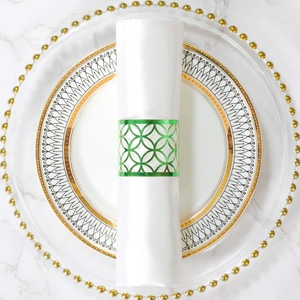 Detalle del servilletero geométrico verde sobre elegantes platos con borde dorado