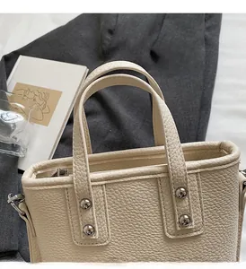 Detail of off-white lychee leather tote bag with silver rivets and D-ring attachments