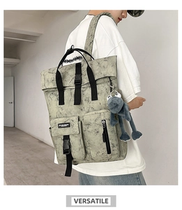 Detail view of large grey marble-patterned backpack featuring a blue plush frog pendant