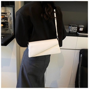 Detail of white PU leather crossbody bag with geometric flap stitching worn by a model