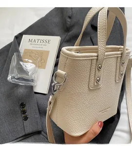 Chic cream leather bucket bag with silver studs on a stylish grey blazer background