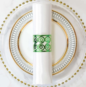 Detailed laser-cut geometric scroll pattern on a green metal napkin ring on white marble