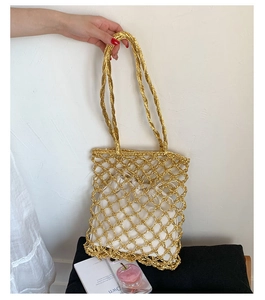 Detail of gold woven mesh tote bag with a white drawstring inner pouch and long handles