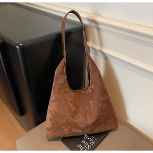 Detail view of large brown tote bag with retro textured suede finish and wide strap