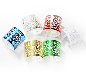 Nahaufnahme von lasergeschnittenen Weinrebenmustern auf bunten Serviettenringen für Hochzeiten