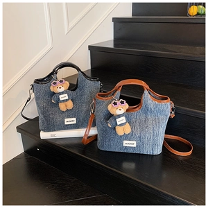 Detail of denim bucket bags with leather trim and cute plush bear charms on stairs