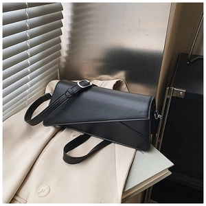 Detail of a minimalist black geometric shoulder bag on a beige blazer with silver buckle