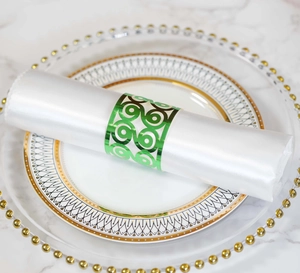 Detail of green metal hollow napkin ring with geometric spiral design on white satin cloth