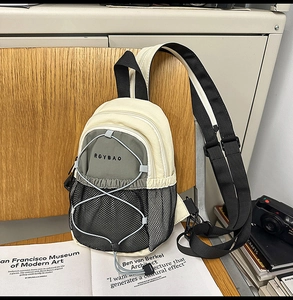 Détail d'un sac à bandoulière en nylon avec poches filet et cordon réglable sur bois