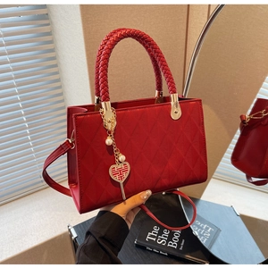 Detail of red quilted tote bag with woven handles and a heart-shaped wedding pendant