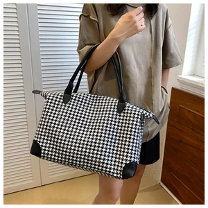 Détail du sac de voyage avec motif pied-de-poule noir et blanc et renforts en cuir