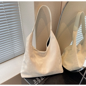 Minimalist cream white hobo tote bag detail with textured matte finish on a book
