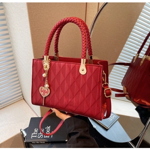 Detailed view of red quilted wedding tote bag with gold hardware and heart pendant