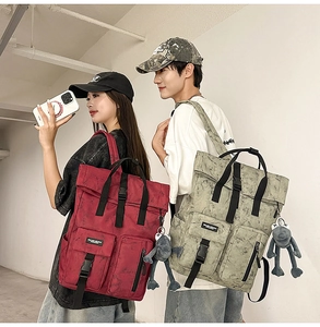 Detail of red and grey-green tie-dye backpacks with utility buckles and plush pendants