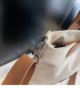 Detailed close-up of dark gunmetal lobster clasp and brown woven strap on canvas tote