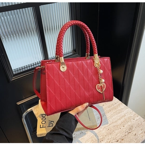 Detail of red quilted bridal tote with woven handle and golden double happiness charm