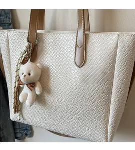 Detail of white woven tote bag featuring soft texture and brown leather handles