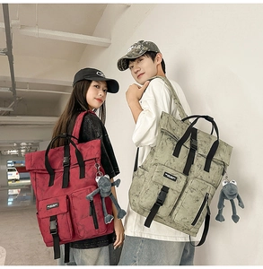 Detail of vintage canvas backpacks with roll-top closure and frog pendant accessories