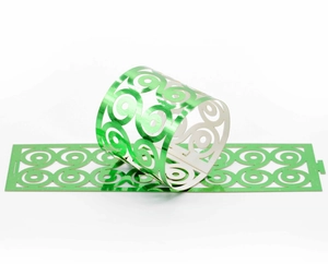Detail of laser-cut green metallic napkin rings featuring intricate swirl patterns