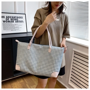 Détail du grand sac de voyage avec motif pied-de-poule bleu et finitions en cuir rose