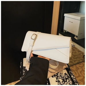 Detail shot of a minimalist white asymmetric geometric crossbody bag with a silver buckle strap