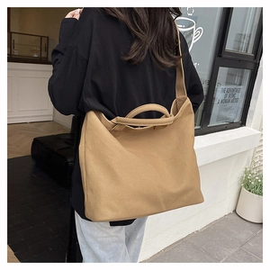 Detail view of khaki canvas tote bag with wide shoulder strap and dual tubular handles